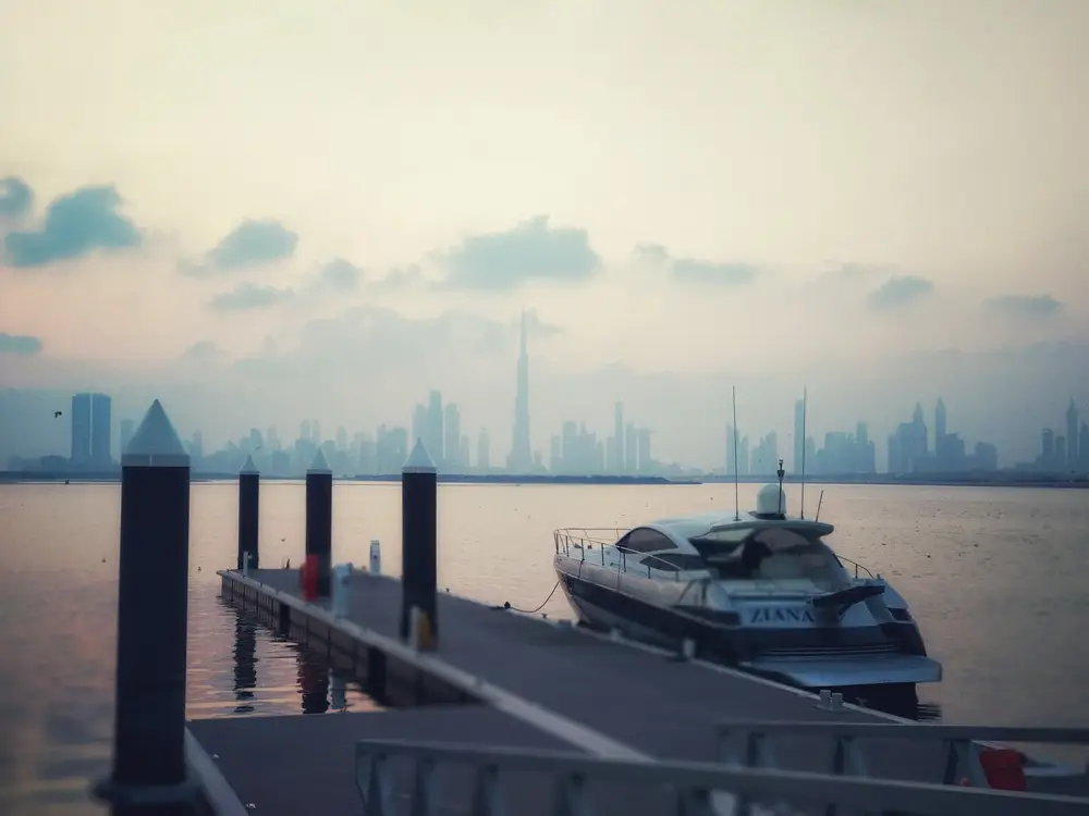 Quiet mooring jetty and yacht facing the misty Dubai skyline at The Cove, Dubai Creek Harbour