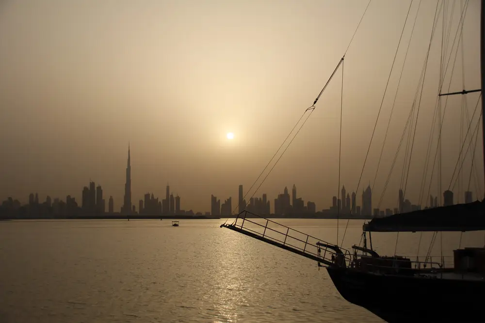 Dhow rigging silhouetted against the hazy Downtown Dubai skyline from the harbour
