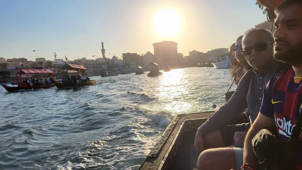 Passengers riding a traditional abra across Dubai Creek in golden light