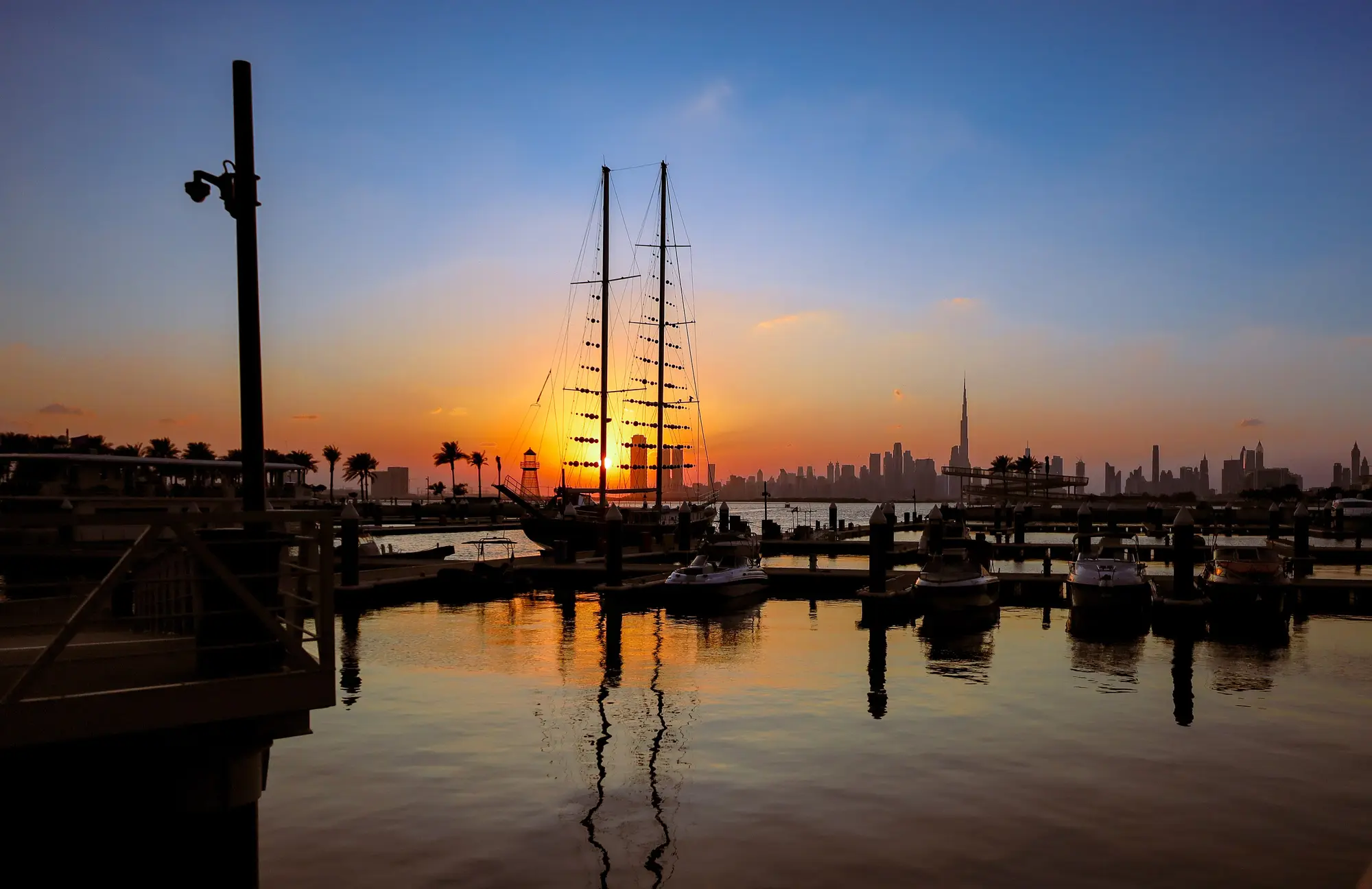 Sunset over Creek Marina at Dubai Creek Harbour with sailing yachts and the Downtown Dubai skyline on the horizon