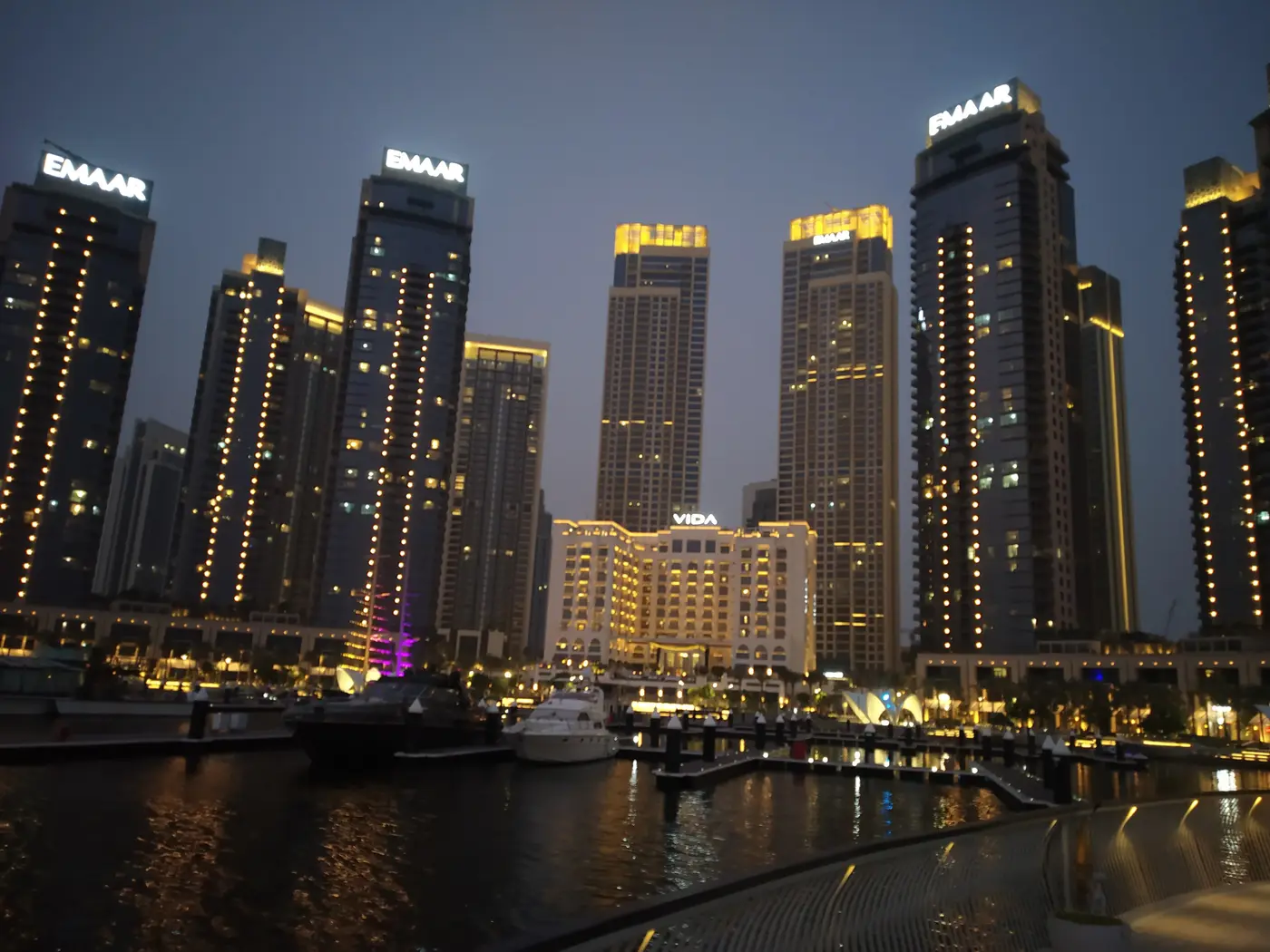 Emaar residential towers and the Vida hotel lit at dusk above Creek Marina at Dubai Creek Harbour